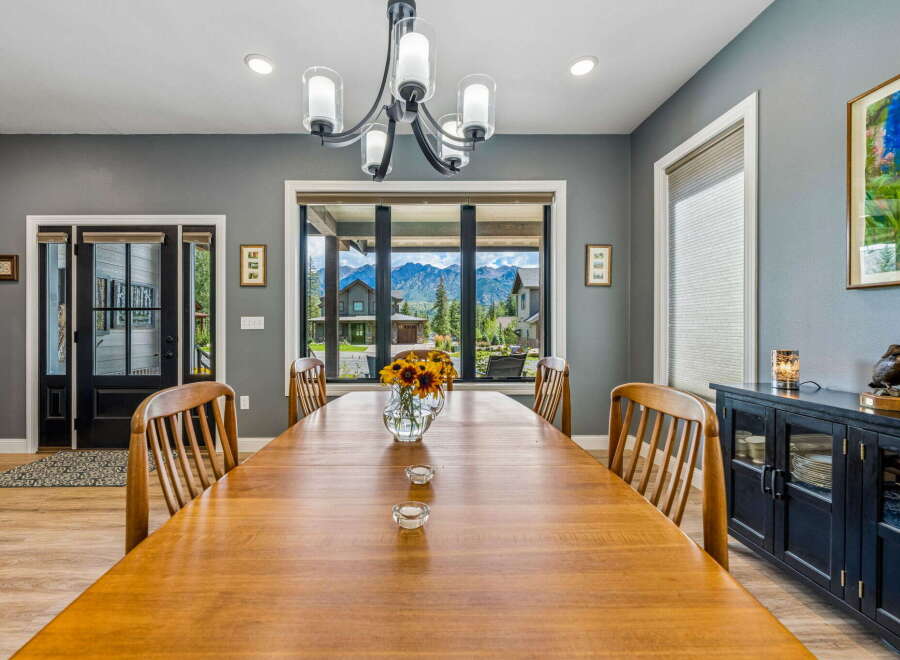 Experience breathtaking mountain views from this elegant dining room, featuring a large wooden table perfect for gatherings.