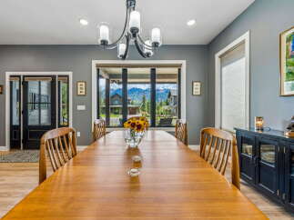 Experience breathtaking mountain views from this elegant dining room, featuring a large wooden table perfect for gatherings.