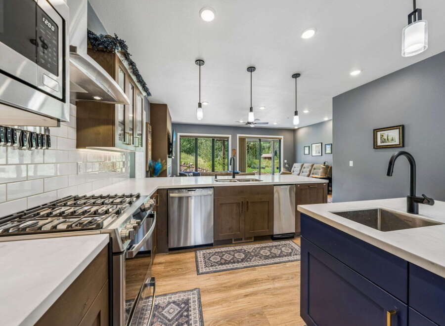Experience modern living in this stunning kitchen, featuring sleek stainless steel appliances, a gas range, and a large island with a deep sink and matte black faucet.
