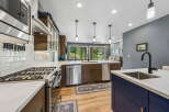 Experience modern living in this stunning kitchen, featuring sleek stainless steel appliances, a gas range, and a large island with a deep sink and matte black faucet.