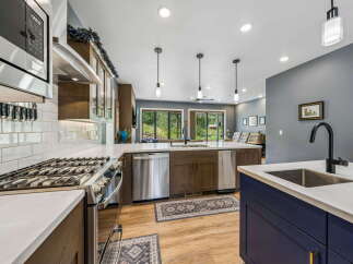 Experience modern living in this stunning kitchen, featuring sleek stainless steel appliances, a gas range, and a large island with a deep sink and matte black faucet.