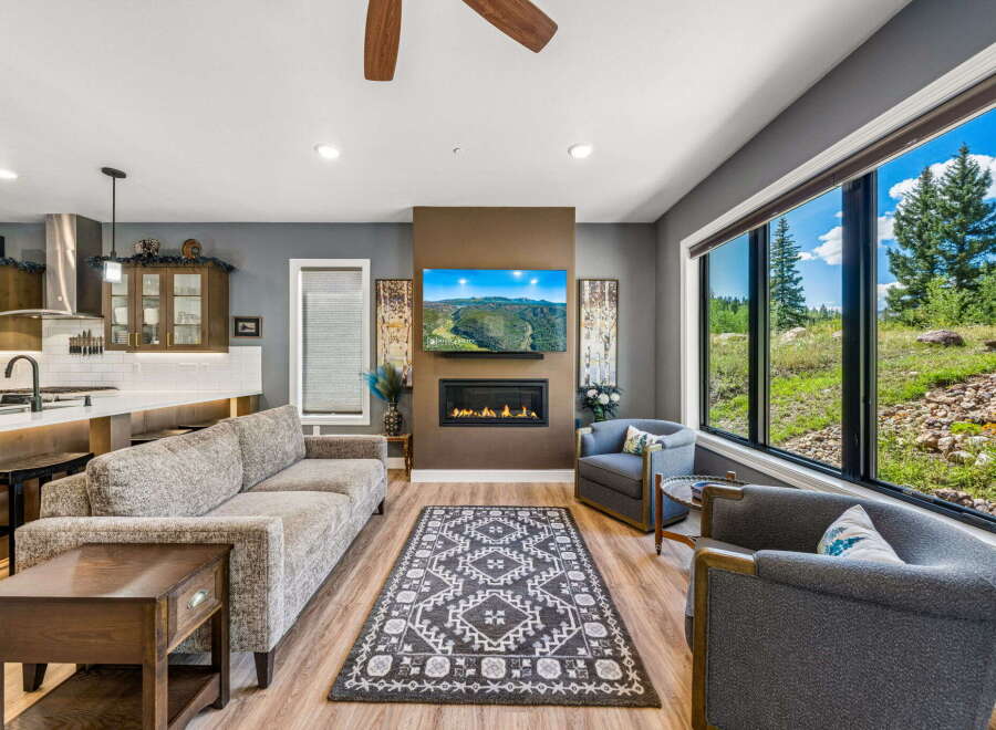 Experience breathtaking mountain views from this stunning living room, featuring a modern fireplace and a large picture window.