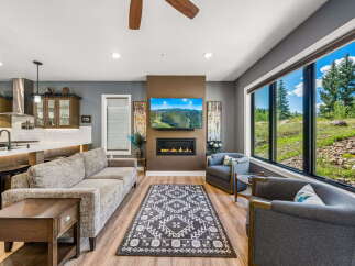 Experience breathtaking mountain views from this stunning living room, featuring a modern fireplace and a large picture window.