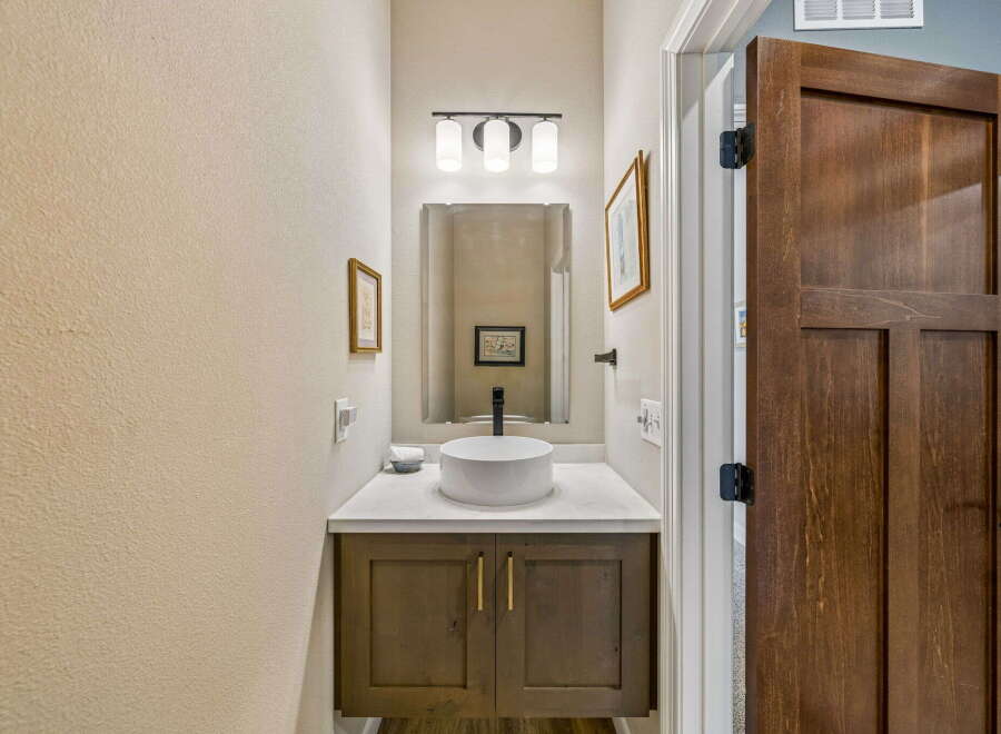 This powder room features a modern vessel sink atop a dark wood vanity with gold hardware.