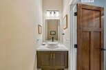 This powder room features a modern vessel sink atop a dark wood vanity with gold hardware.