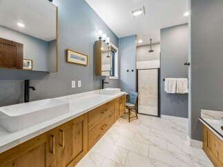 Experience luxury in this modern bathroom featuring a spacious double vanity with vessel sinks and sleek black faucets.