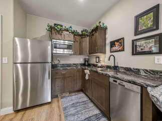Discover this charming kitchen, featuring a sleek stainless steel refrigerator and a convenient microwave above the sink.