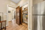Discover ample storage solutions in this home, featuring a spacious pantry filled with board games and a large stainless steel refrigerator.