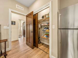 Discover ample storage solutions in this home, featuring a spacious pantry filled with board games and a large stainless steel refrigerator.
