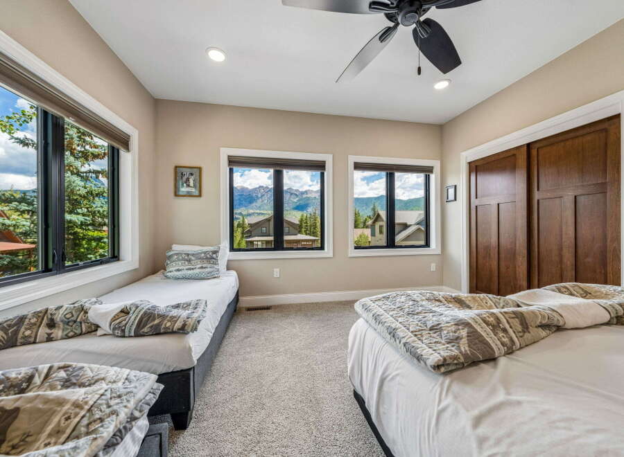 Experience breathtaking mountain views from this spacious bedroom, featuring two comfortable twin beds and a queen-sized bed, perfect for families or groups.