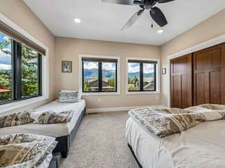 Experience breathtaking mountain views from this spacious bedroom, featuring two comfortable twin beds and a queen-sized bed, perfect for families or groups.