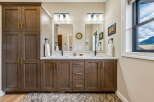 This modern bathroom features a spacious double vanity with ample storage, complemented by sleek gold hardware and a clean white countertop.
