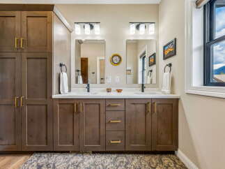 This modern bathroom features a spacious double vanity with ample storage, complemented by sleek gold hardware and a clean white countertop.