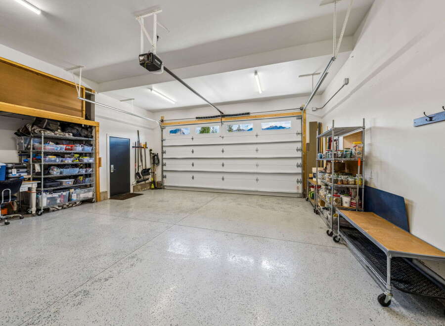 Discover ample storage and organization in this spacious garage, featuring a large overhead storage unit and multiple shelving units.