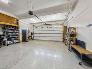 Discover ample storage and organization in this spacious garage, featuring a large overhead storage unit and multiple shelving units.