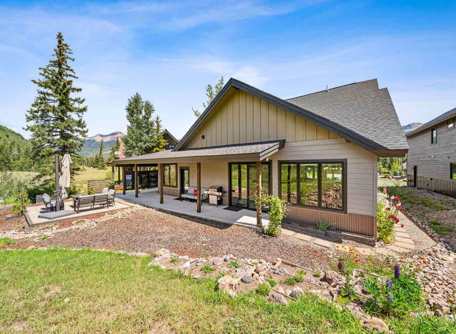 Experience mountain living in this stunning home featuring a spacious covered patio perfect for outdoor entertaining, complete with a grill and comfortable seating.