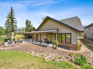 Experience mountain living in this stunning home featuring a spacious covered patio perfect for outdoor entertaining, complete with a grill and comfortable seating.