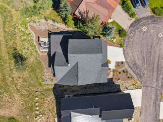 Experience stunning aerial views of this property, showcasing a beautifully landscaped yard with a patio area perfect for outdoor entertaining.