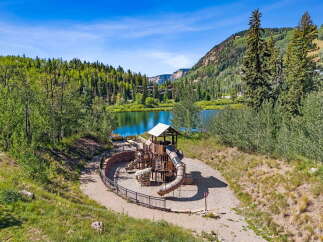Discover a family-friendly paradise with this stunning playground overlooking a serene lake, perfect for outdoor recreation.