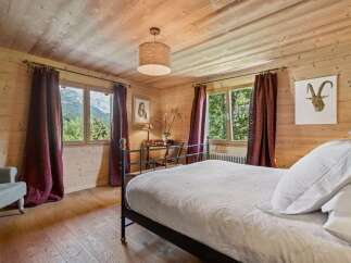 Experience rustic charm in this beautifully appointed bedroom, featuring warm wood paneling and a cozy ambiance.