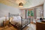 Experience rustic charm in this inviting bedroom, featuring a cozy metal-frame bed adorned with crisp white linens and a plush throw.
