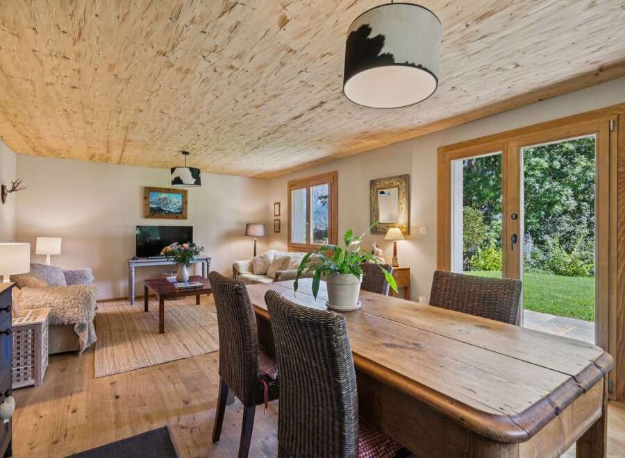Experience rustic charm in this inviting living and dining area, featuring a natural wood-paneled ceiling and warm hardwood floors.