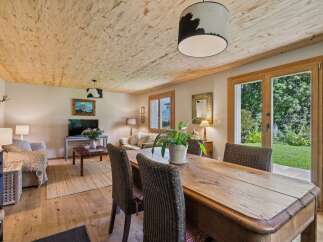 Experience rustic charm in this inviting living and dining area, featuring a natural wood-paneled ceiling and warm hardwood floors.