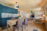 Experience cozy living in this charming open-concept space, featuring a modern kitchen with deep blue cabinetry and a rustic wooden dining table perfect for intimate meals.