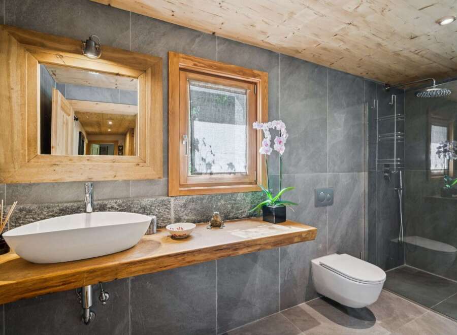 Experience rustic luxury in this modern bathroom featuring a floating live-edge wood vanity with a vessel sink.