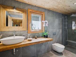 Experience rustic luxury in this modern bathroom featuring a floating live-edge wood vanity with a vessel sink.