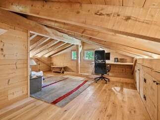 Discover this charming attic workspace, bathed in natural light and featuring a rustic wooden design.