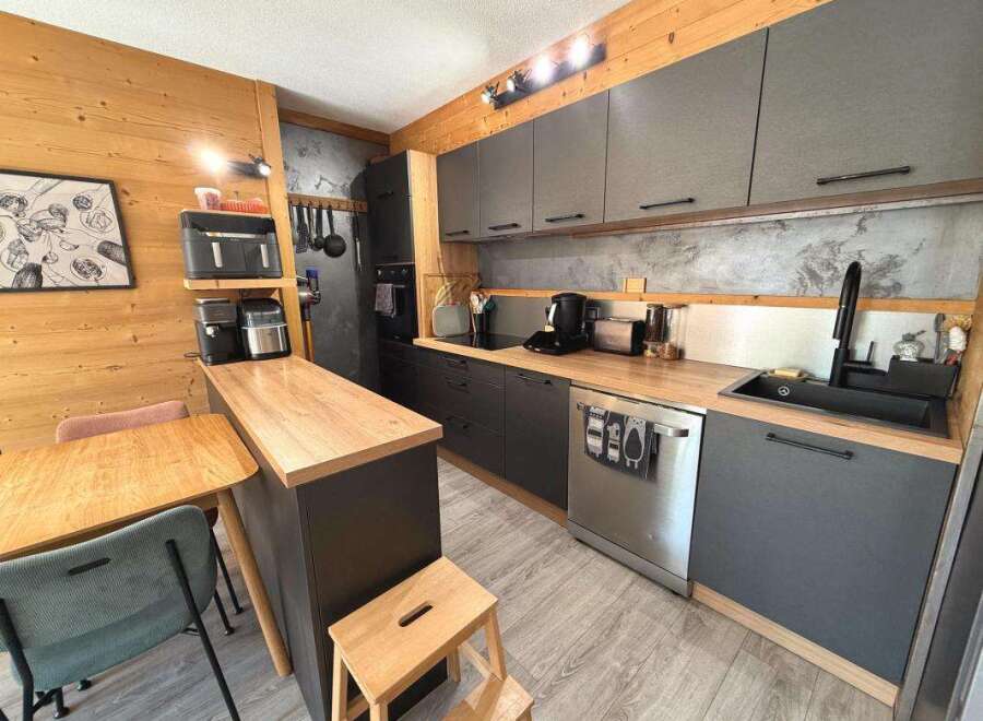 Discover this modern kitchen featuring sleek grey cabinetry and warm wooden countertops, perfect for a cozy yet functional living space.