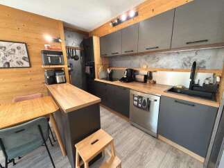 Discover this modern kitchen featuring sleek grey cabinetry and warm wooden countertops, perfect for a cozy yet functional living space.