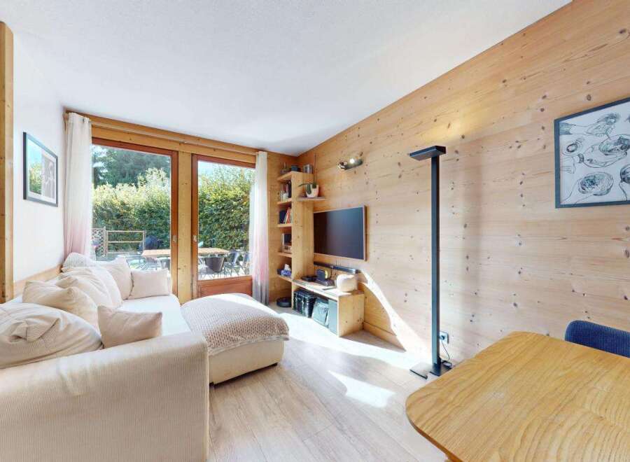 Experience cozy living in this charming mountain retreat, featuring a comfortable sectional sofa and a warm, wood-paneled living area.