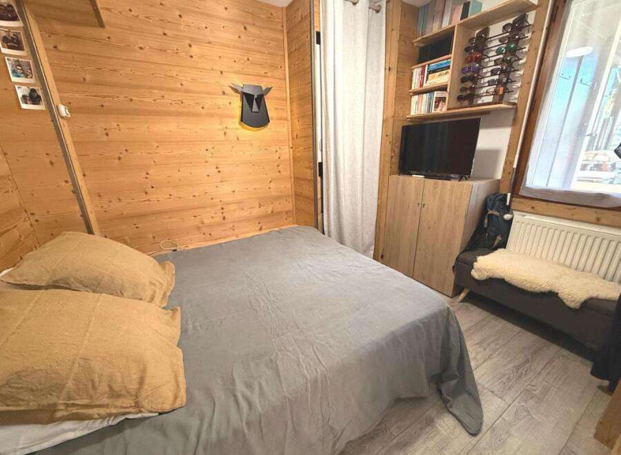 Experience cozy mountain living in this charming bedroom featuring warm wood paneling and a comfortable bed.