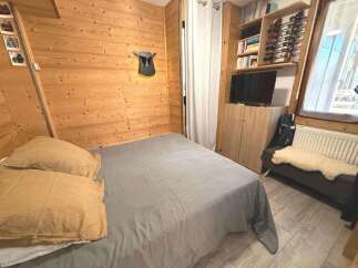 Experience cozy mountain living in this charming bedroom featuring warm wood paneling and a comfortable bed.