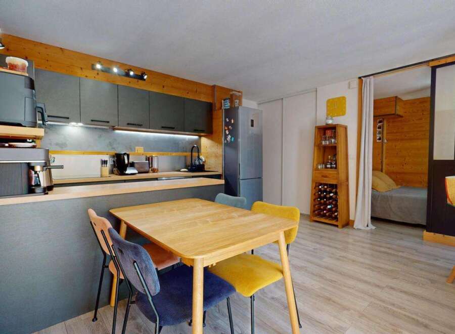 Discover this charming studio apartment featuring a modern kitchenette with sleek grey cabinetry and integrated appliances, perfect for preparing meals.