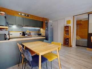 Discover this charming studio apartment featuring a modern kitchenette with sleek grey cabinetry and integrated appliances, perfect for preparing meals.