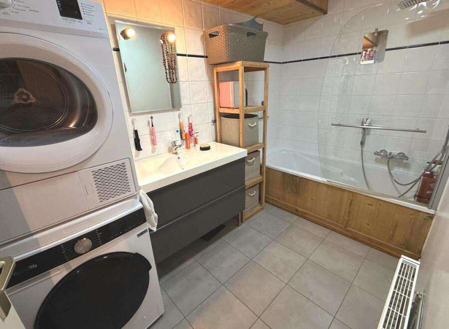 This bathroom features a stacked washer and dryer for ultimate convenience, alongside a spacious vanity with ample storage.