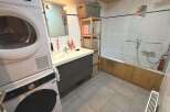 This bathroom features a stacked washer and dryer for ultimate convenience, alongside a spacious vanity with ample storage.