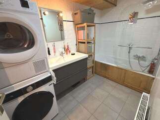 This bathroom features a stacked washer and dryer for ultimate convenience, alongside a spacious vanity with ample storage.