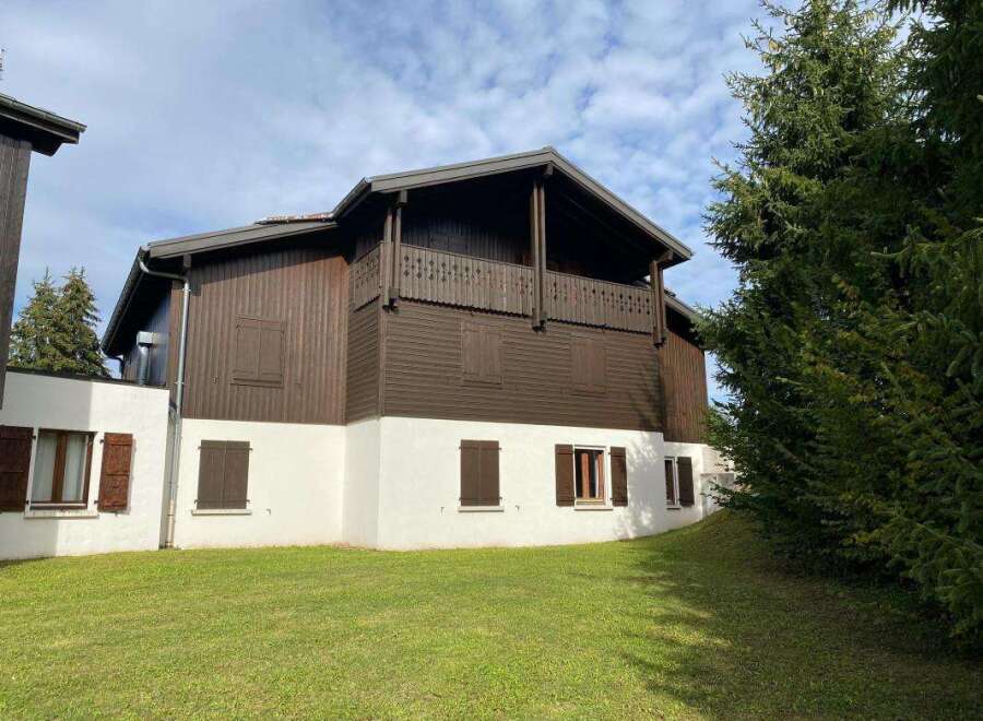 Charming wooden chalet-style home featuring a dark brown exterior with white accents and traditional wooden shutters.