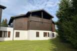 Charming wooden chalet-style home featuring a dark brown exterior with white accents and traditional wooden shutters.