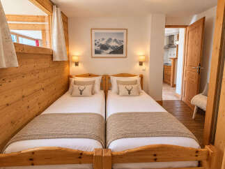 Experience cozy mountain living in this charming bedroom featuring two twin beds adorned with rustic deer-themed pillows and warm, textured throws.