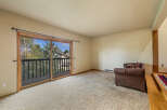 Step out onto the private balcony from this spacious living area, offering serene views of the surrounding trees and sky.