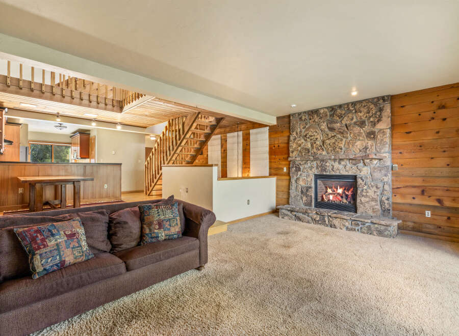 Cozy living room featuring a large stone fireplace and warm wood paneling.