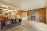 Cozy living room featuring a large stone fireplace and warm wood paneling.
