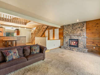 Cozy living room featuring a large stone fireplace and warm wood paneling.