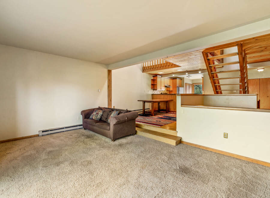This spacious living area features a cozy brown sofa with decorative pillows, perfect for relaxing.