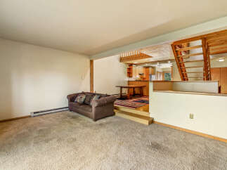 This spacious living area features a cozy brown sofa with decorative pillows, perfect for relaxing.